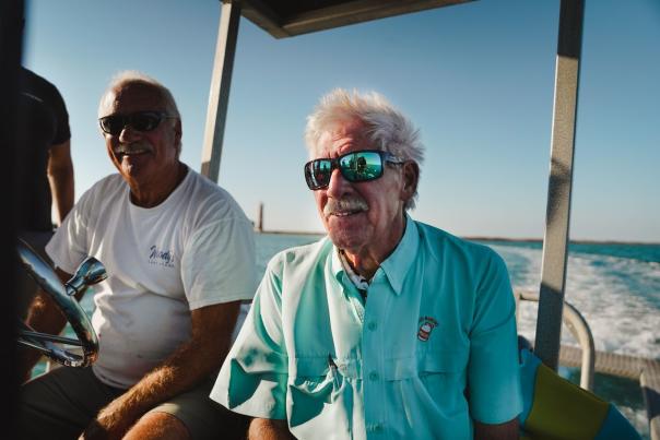 Two men on a boat in the ocean wearing sunglasses.