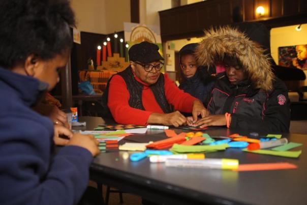 A black family works on a Kwanzaa craft at a table