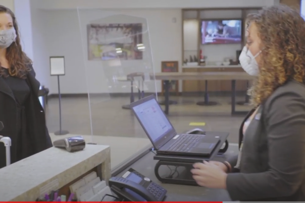 A traveler checks in at a hotel desk during COVID.