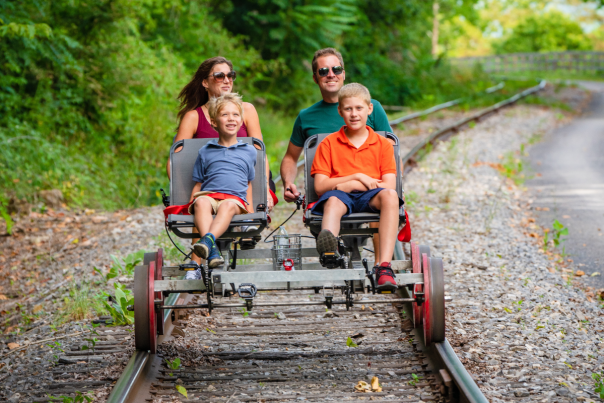 Family of four enjoying the Tracks and Yaks rail biking and kayaking adventure in Allegany County, Maryland, on a sunny summer day.