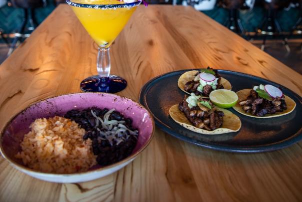 table with tacos, rice and beans, and a margarita