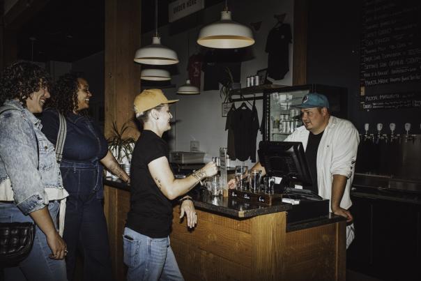 Three people ordering drinks at a bar.