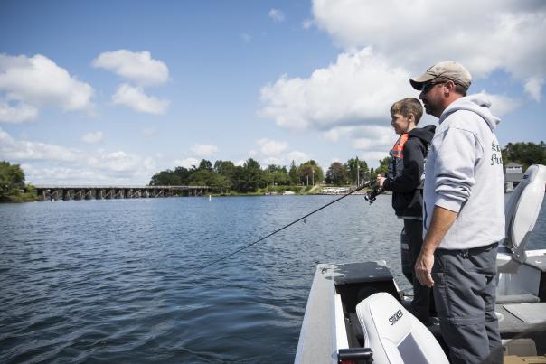 Anglers fishing from a boat on a calm lake near Minocqua, Wisconsin, with shoreline homes in the background.