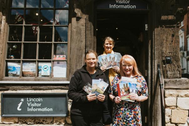 3 people stood outside the Visitor Information Centre in Lincoln holding flyers
