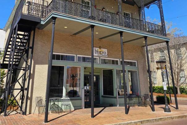 Two story historic brick building with wrought iron balcony and stairs