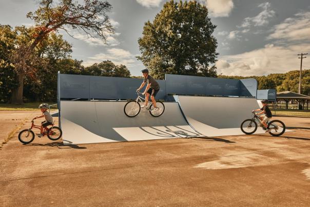 Three people riding bikes on a ramp in a bike/skate park.
