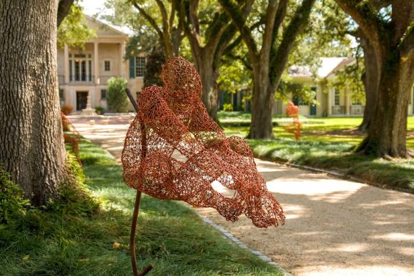 A wire sculpture sits in an outdoor garden