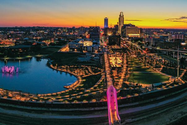 A vibrant sunset skyline shot of Omaha, Nebraska showing pink lights from Heartland of America Park and Farnam Pier.