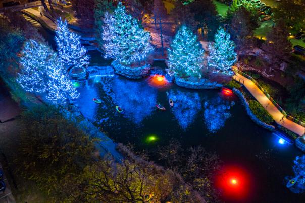 Kayakers on the San Antonio River with trees lit with holiday lights