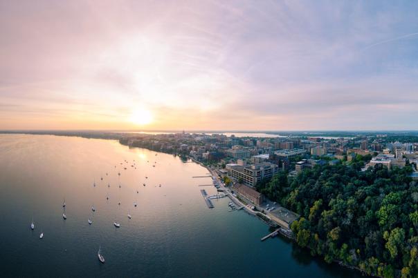 A wide drone image of the city at sunset with Lake Mendota in the foreground