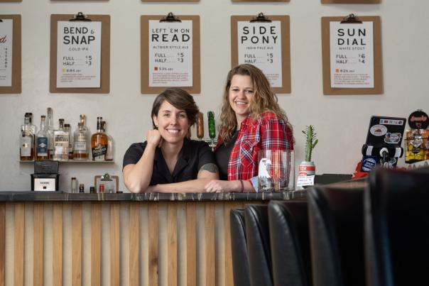 Two women sit behind the bar at ladybird brew