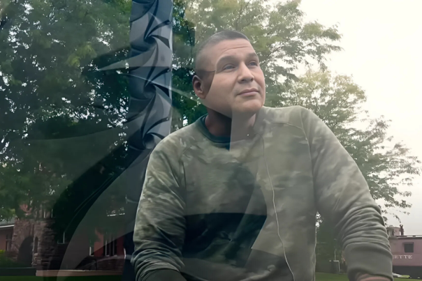 A person sitting in front of his sculpture, gazing thoughtfully, with a reflective surface overlay featuring his art.