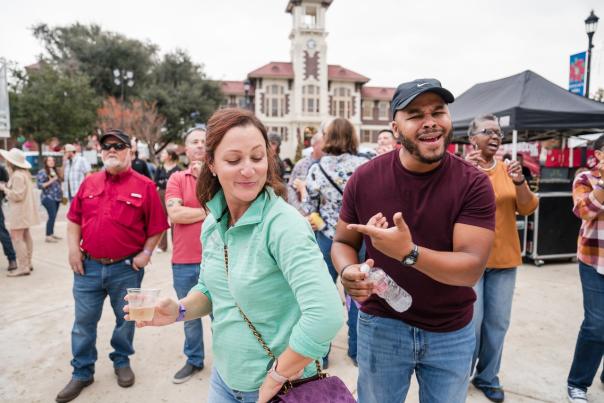 woman in green shirt and man in burgandy shirt dance at smoke and barrel festival in downtown lake charles