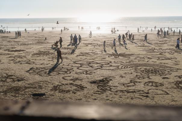 People biking, walking and creating sand art on the beach