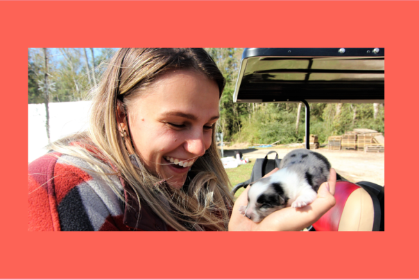 A woman laughs while gently cradling a newborn puppy that, at first glance, looks like a piglet.