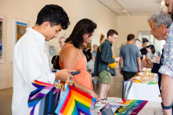 People browse a table with rainbow flags and informational materials at a pride event at 21c in Bentonville, AR.
