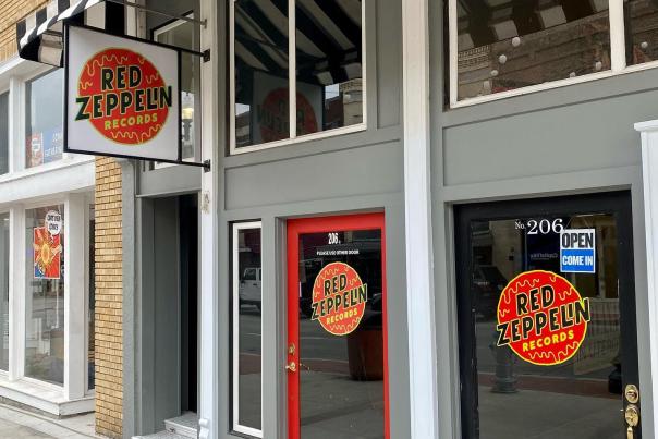 Storefront of Red Zeppelin Records with red and black doors and striped awning