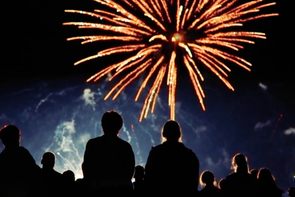 a group of people sit outside and watch a firework display in Devon