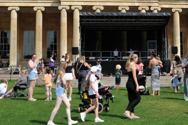 Lots of people walking around in front of Pittville Pump Room at a family event