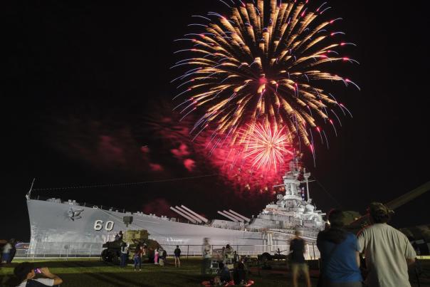 Red fireworks explode at night above the USS ALABAMA battleship