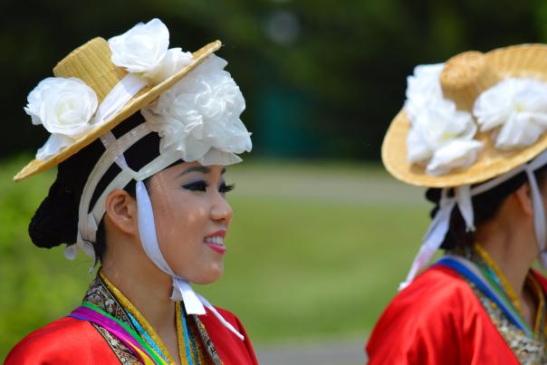 Korean dancers dressed in red with straw hats with white flowers