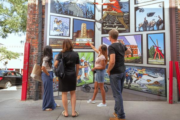 Four people admiring a public outdoor mural on the side of a bulding in downtown Ann Arbor