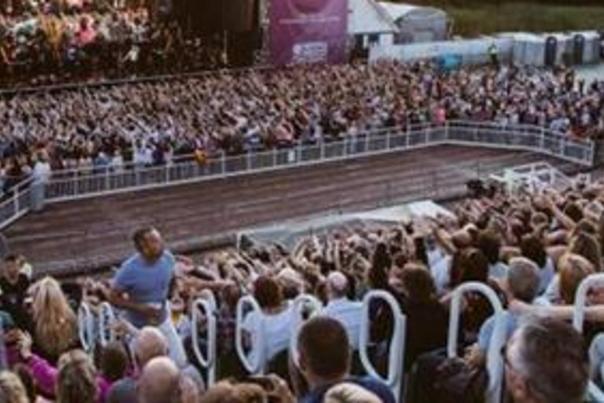 An open air stage in Scarborough at sunset with a large audience