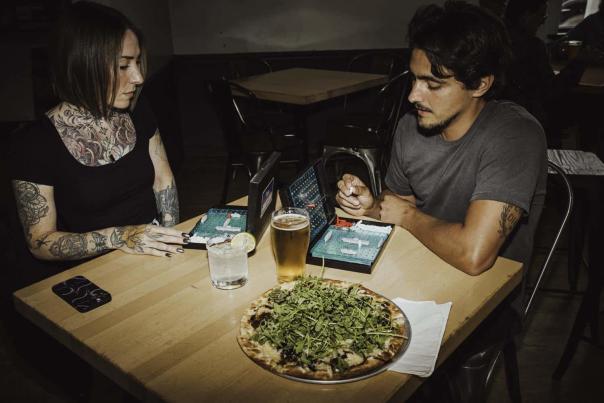 Two people play battleship at a restaurant.