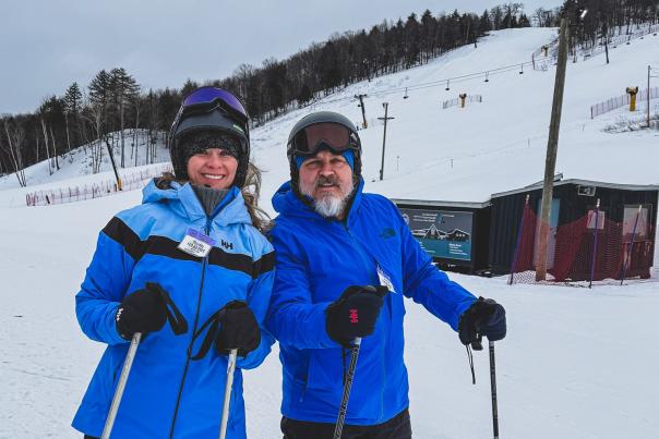 Chris + Melissa posing on their skis, geared up in front of Marquette Mountain