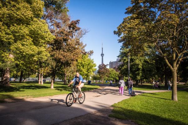 A person rides a bike through Trinity Bellwoods park