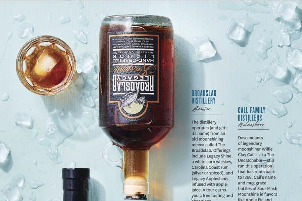 Glass bottle of burbon-looking liquid laid out on a table-top with ice chips.