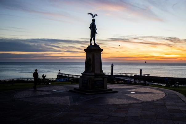 Captain Cook memorial monument, silhouetted at sunset, with a seagull proudly perched on his head