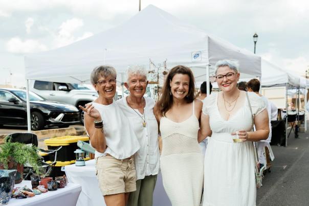 group of women in white linen outfits shop during a festival