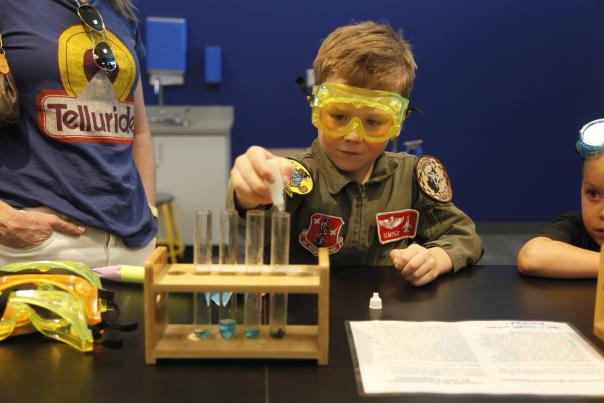 Child experimenting with test tubes at Discovery Lab under staff supervision