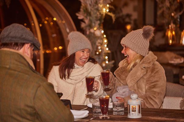 Two ladies in bobble hats enjoying mulled wine at a Christmas market at Wild Thyme and Honey