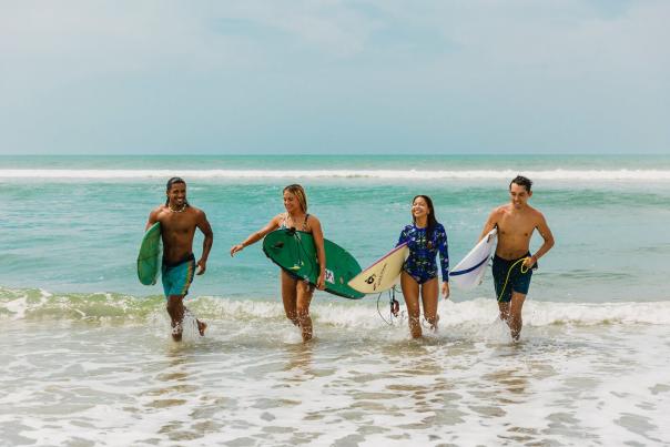 Cuatro surfistas divirtiéndose en las olas de Playa El Palmar, Riviera Pacífica, Panamá