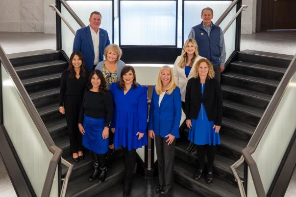 Photo of 9 people wearing blue + black standing on staircase smiling