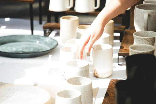 A person placing down a ceramic mug next to other ceramic mugs.