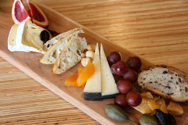 wooden charcuterie board with cheese, nuts and fruit
