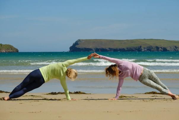 Two people doing yoga on the sandy beach at the Witterings