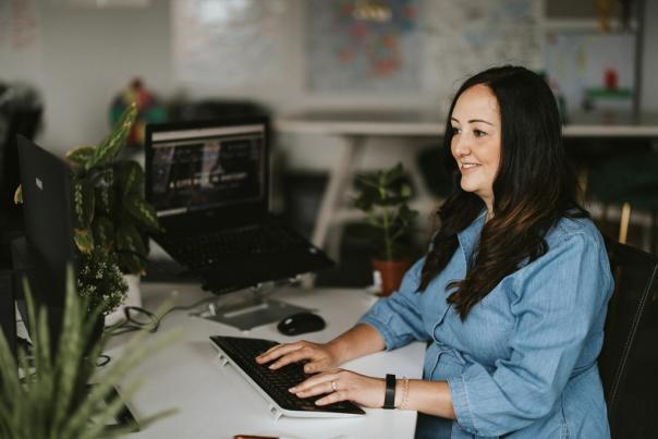 A woman sat at a desk typing on a keyboard