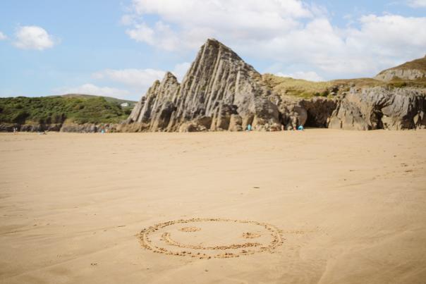 A smiley face in the sand at Three Cliffs Bay