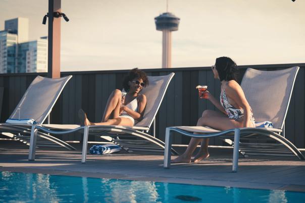 Two girls talking poolside on lounge chairs