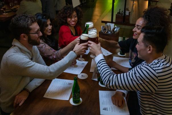A group of friends cheers with beers at a restaurant in Toronto