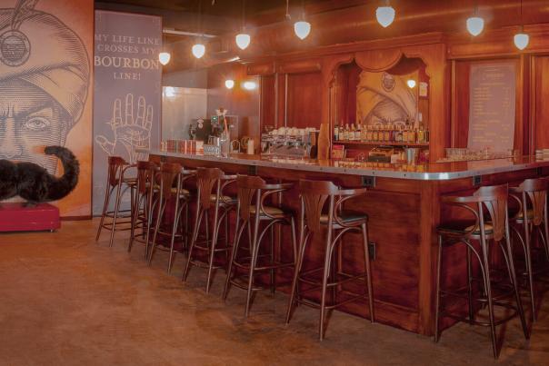 A warm toned bar with several stools pulled in around. On the left the logo for Second Sights fills the wall with a 3-D, fuzzy, mustache.