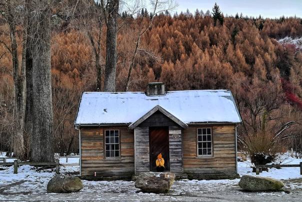 Person sits outside histroric Police Hut Arrowtown