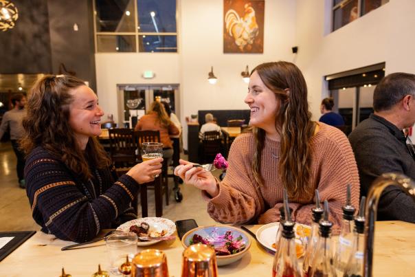 Two white women enjoy a meal and cocktails together at Seven Acre Dairy Company