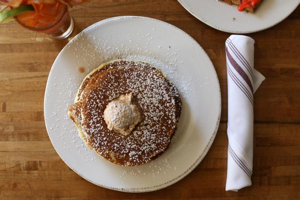 Browned pancake with a dollop of butter on top, powdered sugar spread