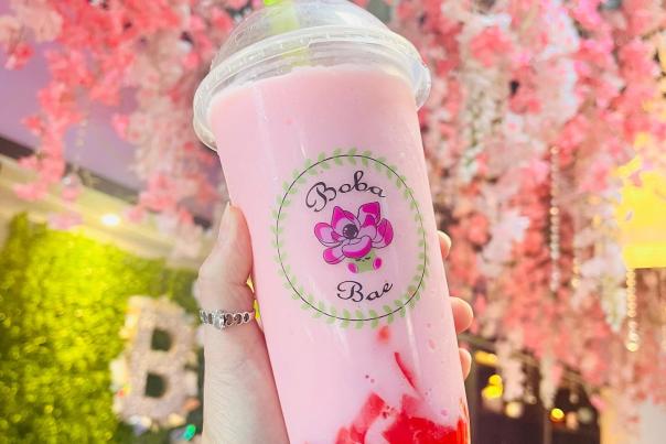 Photo of hand holding boba bae pink drink