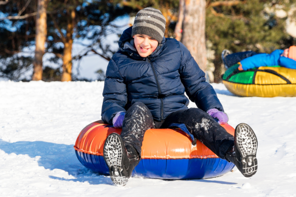 boy snow tubing with a smile on face